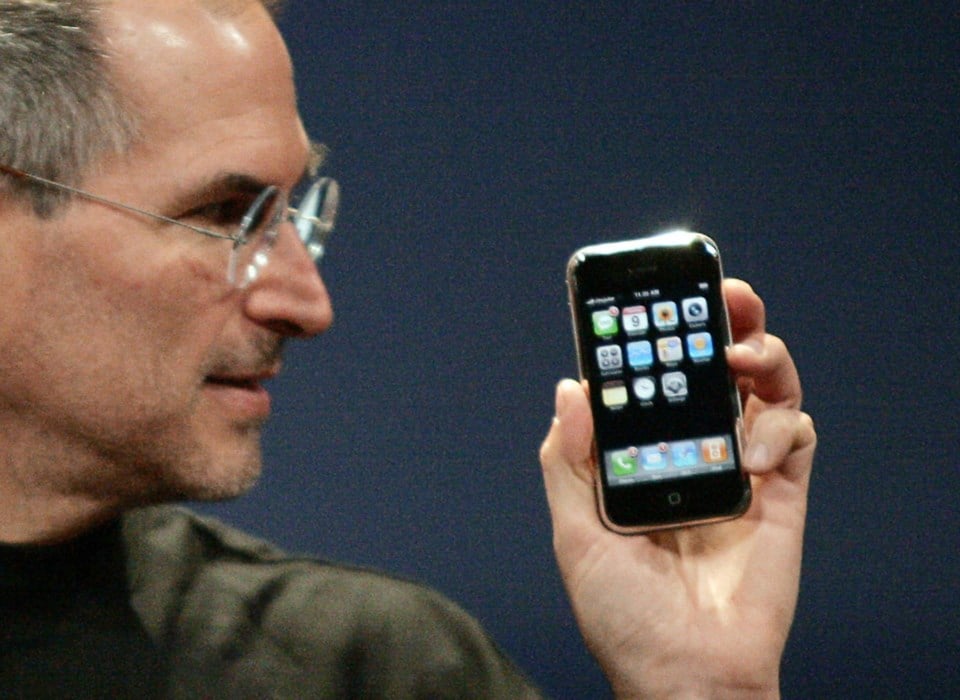 Imagem primeiro iPhone e Steve Jobs